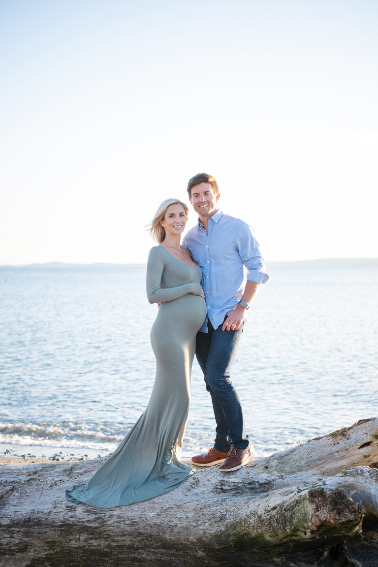 Gorgeous man and wife expecting their first child in front of the ocean at sunset.